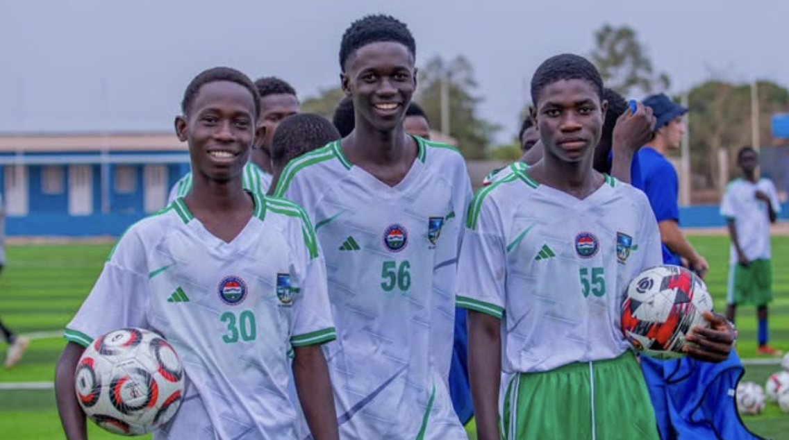 Three young players smiling with footballs